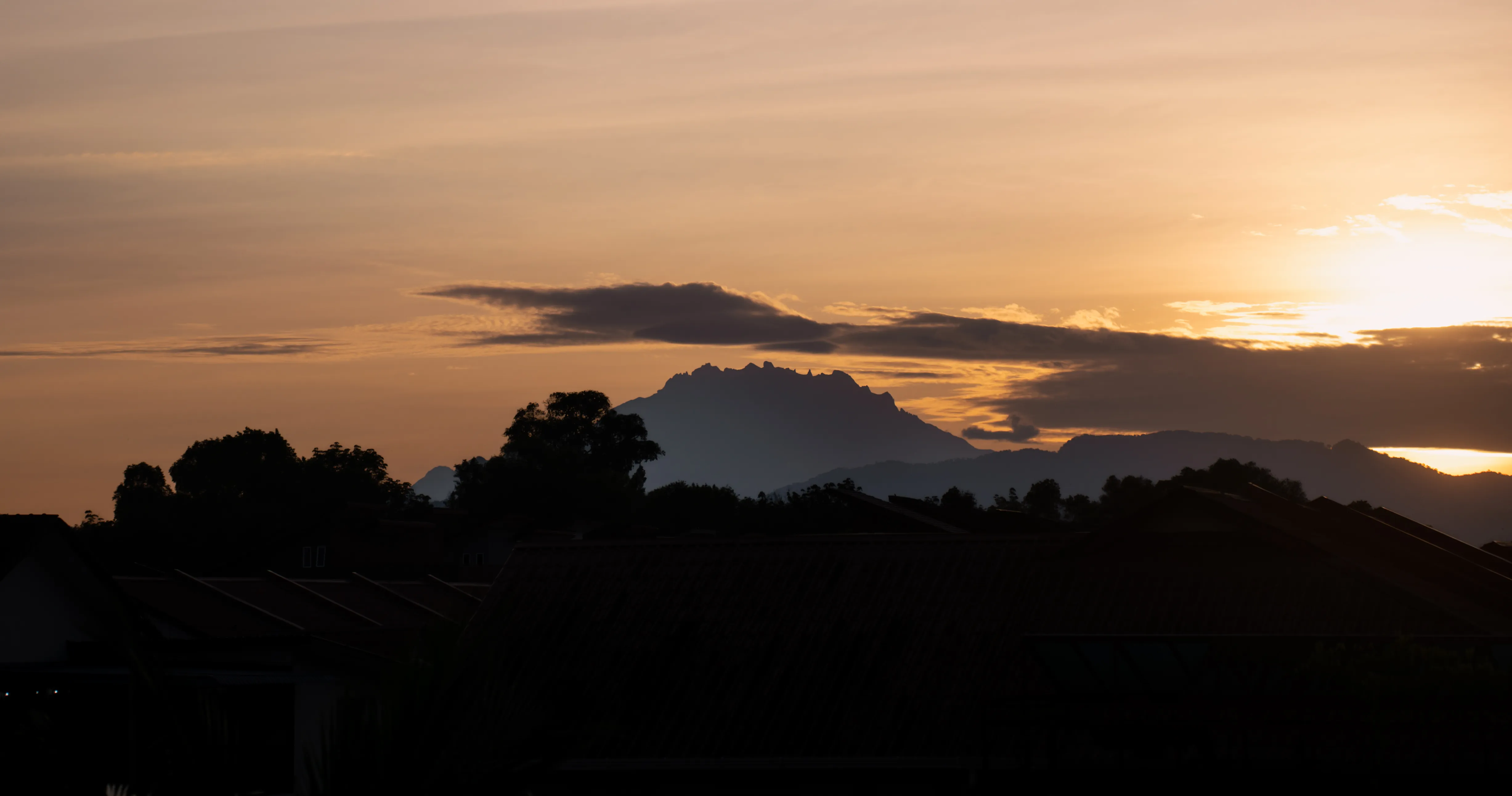 Mount Kinabalu silhouetted beneath a warm sunset sky