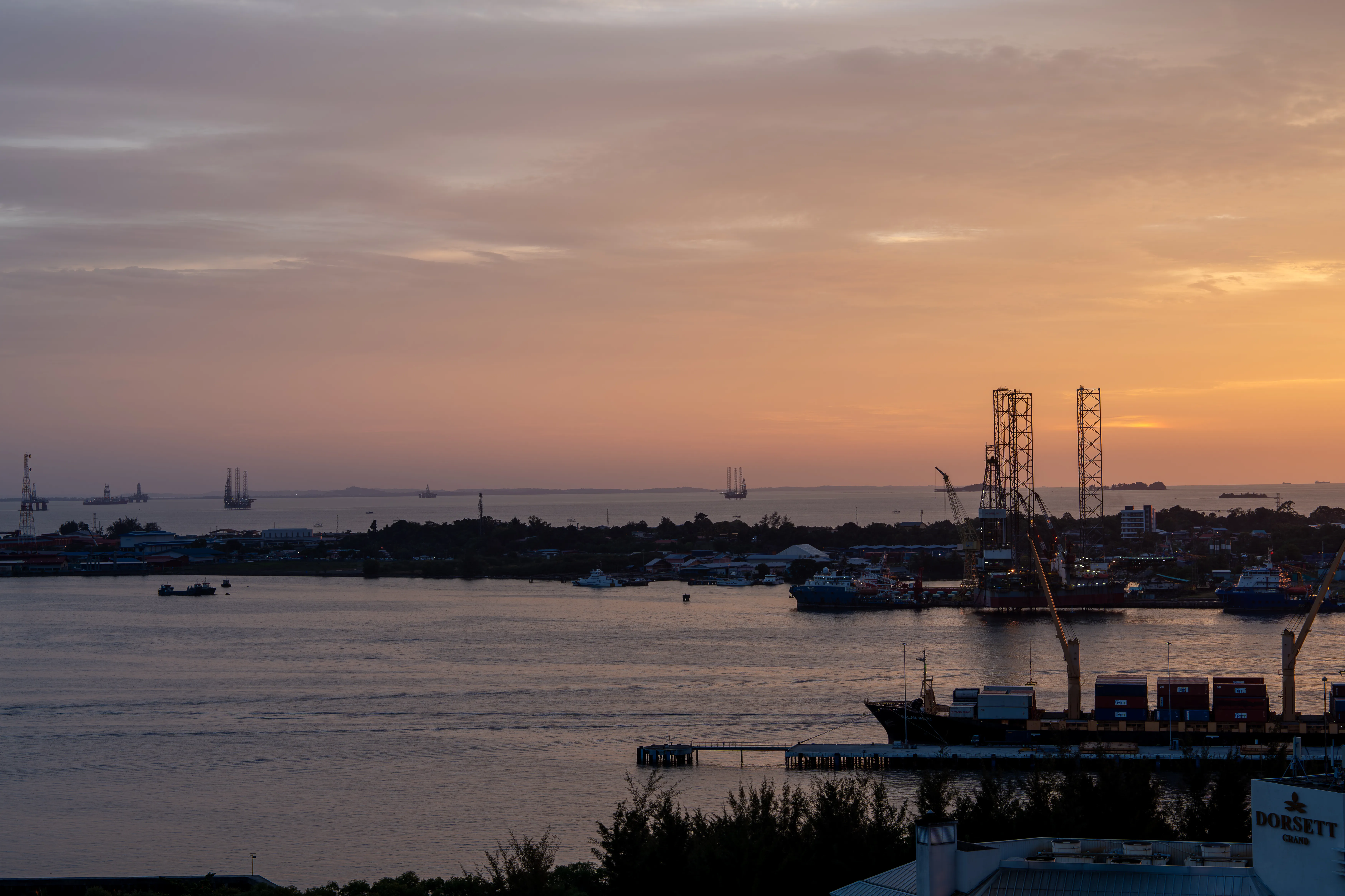 Harbour and offshore structures beneath a warm sunset sky