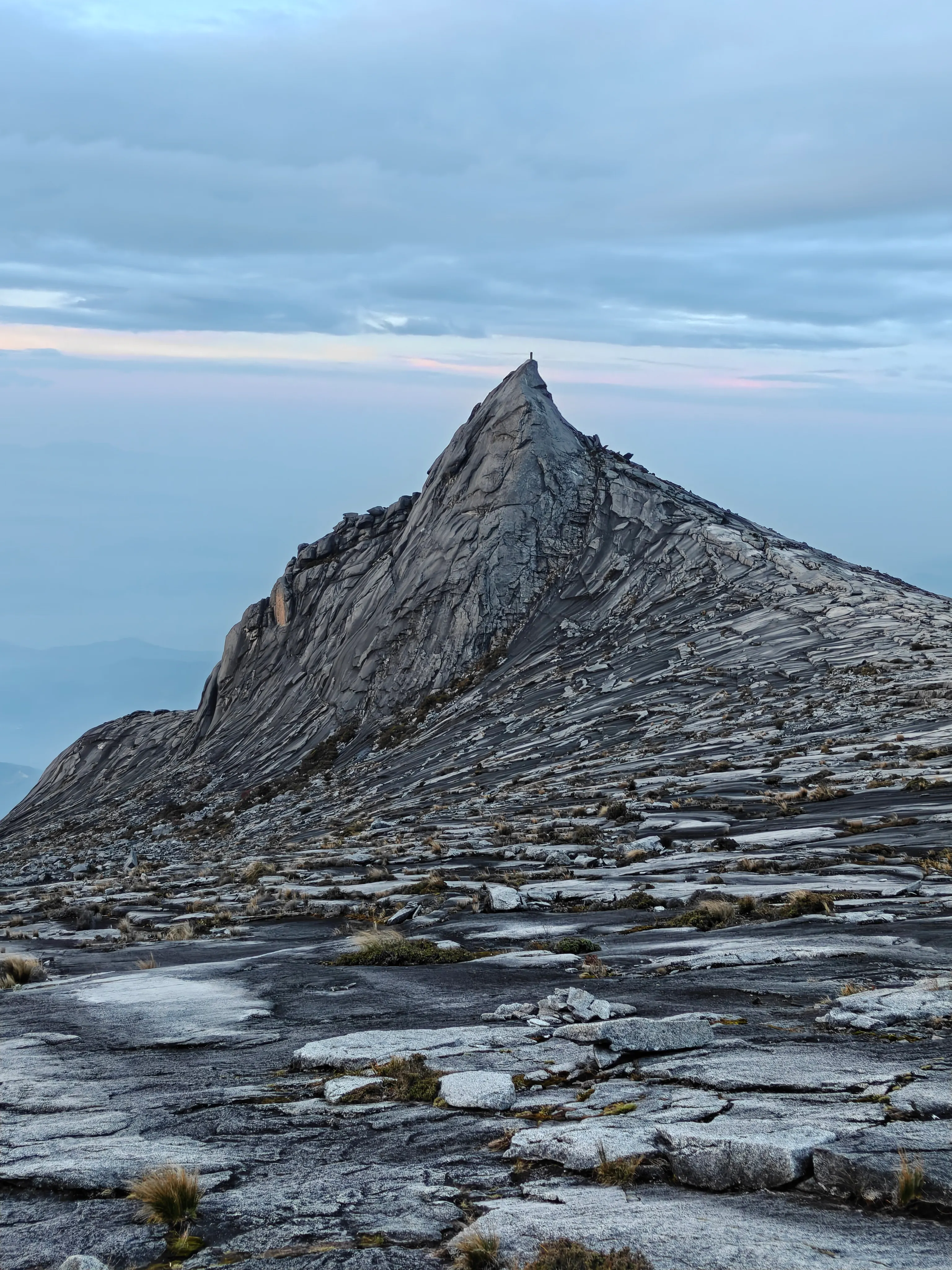 Granite mountain ridge beneath a cloudy blue sky